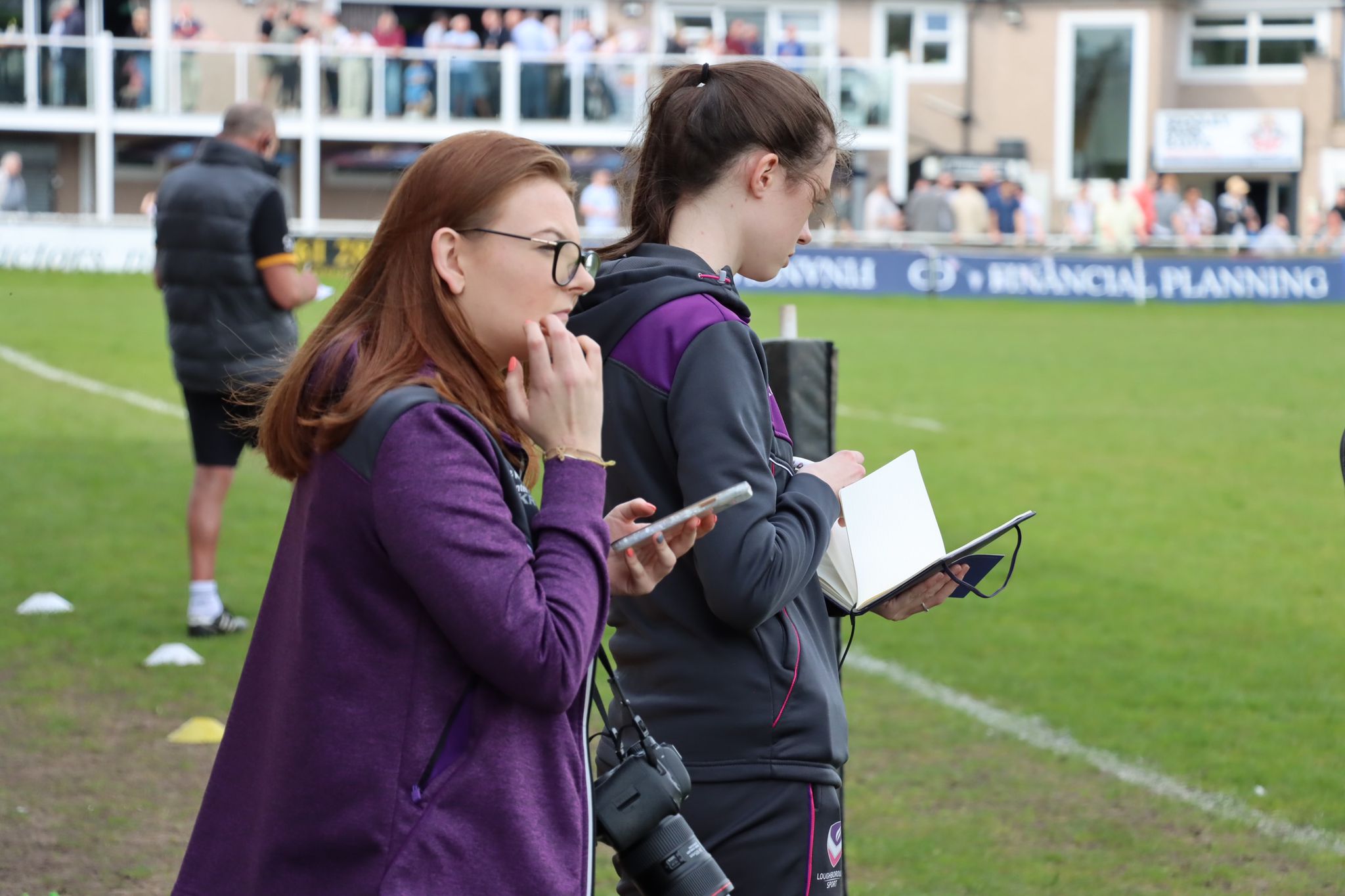 Lily Patey holding a camera at a rugby match 